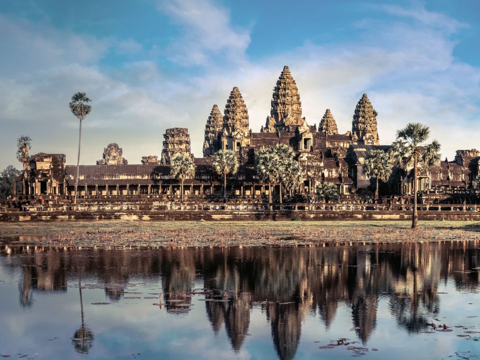 Angkor Vat (Cambodge, XIIe siècle) : cinq tours disposées en quinconce, la plus haute au centre, entourées de galeries, une composition qui figure le mont Meru et ses sommets. — © Expedia Temple khmer en grès à cinq tours en quinconce, précédé de palmiers à sucre et reflété dans un bassin aux nénuphars.
