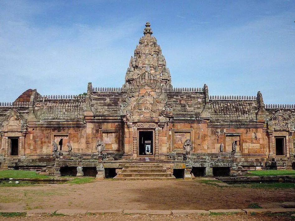 Façade d'un sanctuaire khmer en grès rose avec galerie basse, porte centrale et tour sculptée en ogive.